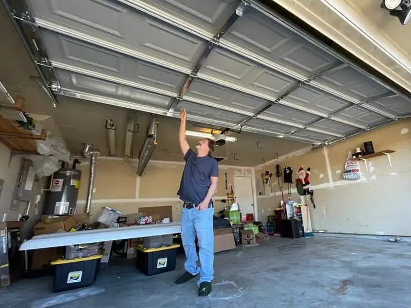 Man inspecting garage door in a cluttered space