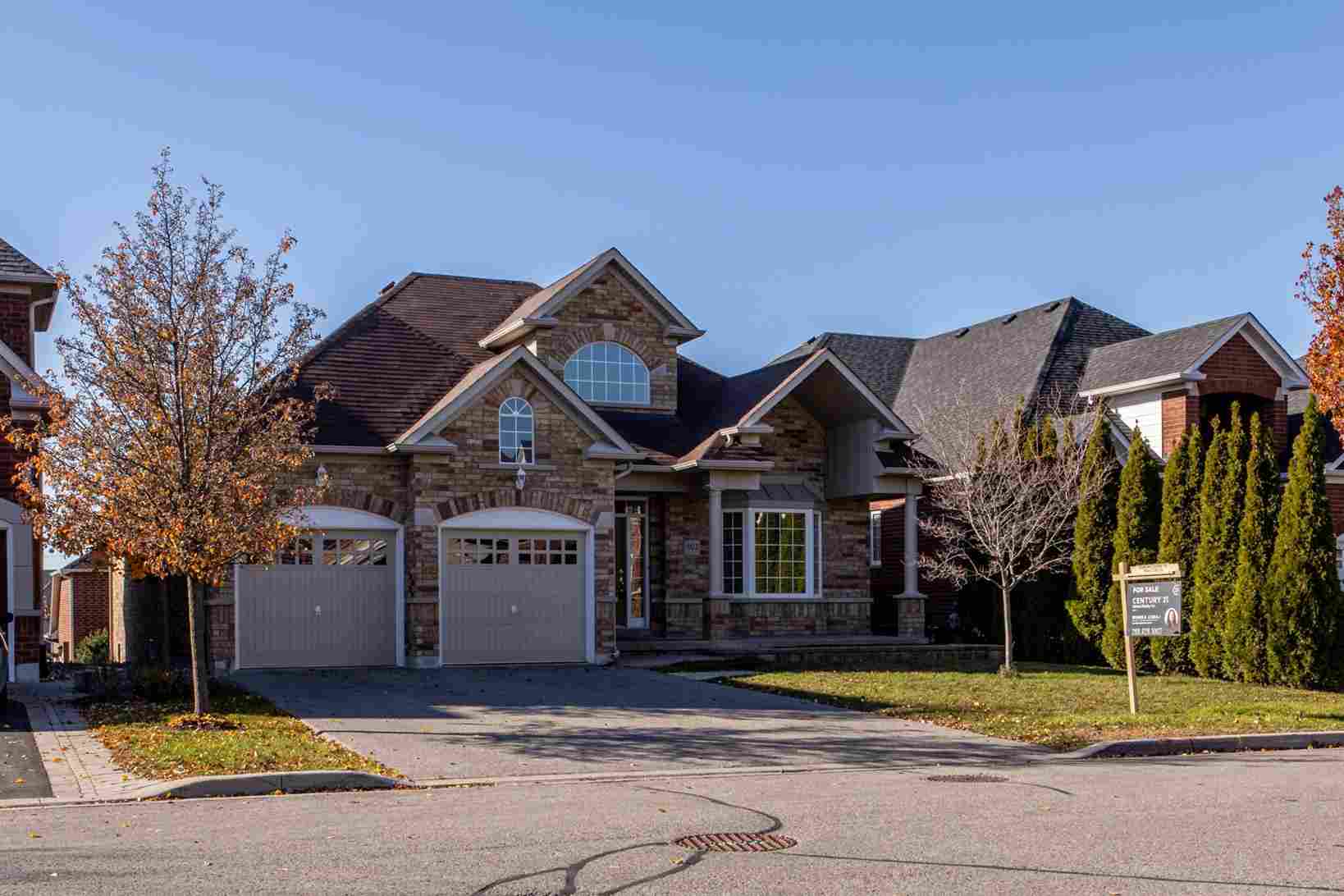 Stone house with a double garage door during autumn in a suburban neighborhood